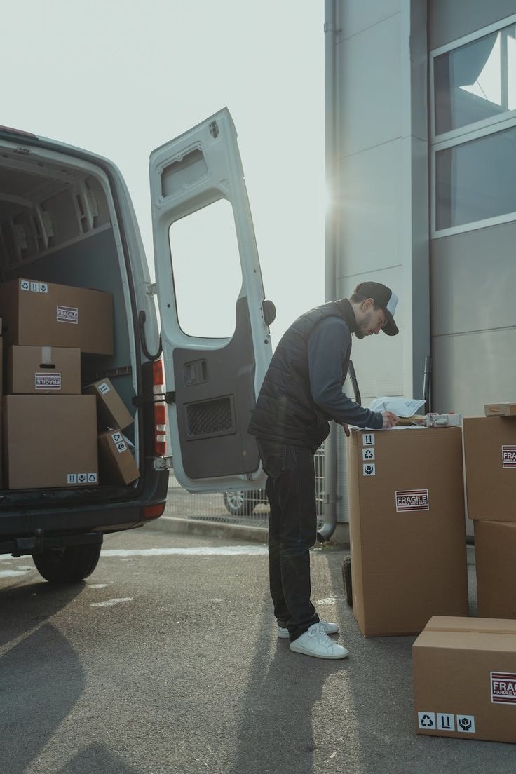 Delivery professional checking parcels beside a delivery van