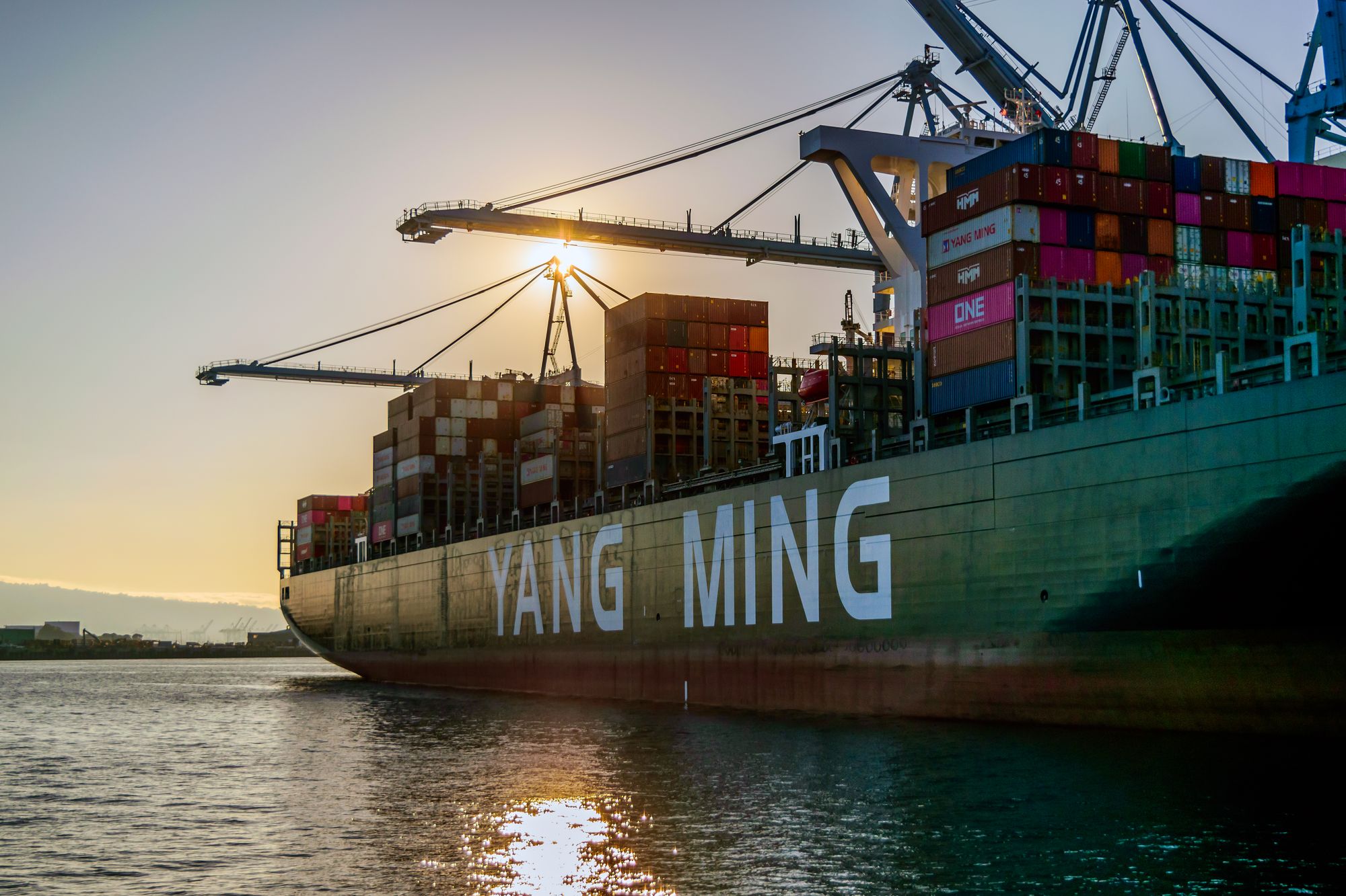 Cargo ship and port cranes at sunset